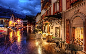 Rainy Evening Street Scene in a Swiss Alpine Town with Cafe and Warm Lights HD wallpaper