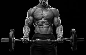 Black and white portrait of a muscular bodybuilder performing a barbell curl in the gym HD wallpaper
