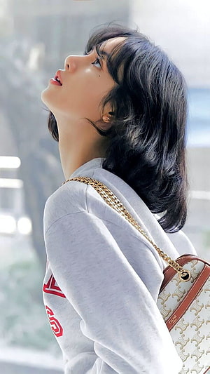 Lisa from BLACKPINK in a grey sweatshirt with a Celine chain bag, looking upward in soft natural light HD phone wallpaper