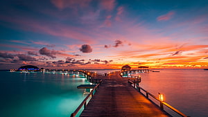Maldives Overwater Resort Pier at Sunset with Vibrant Sky and Turquoise Lagoon HD wallpaper