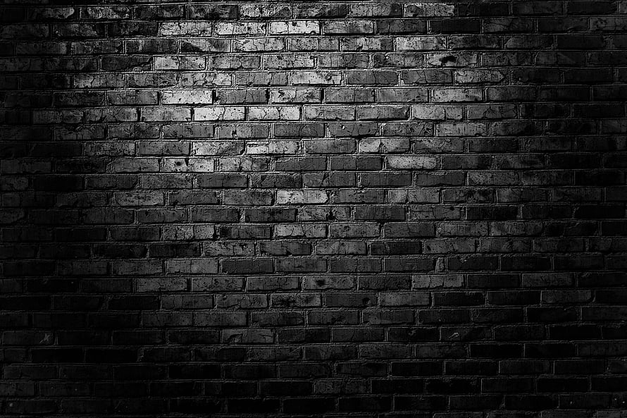 Moody Black Brick Wall Texture with Dramatic Lighting and Deep Shadows HD wallpaper