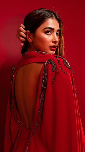 Pooja Hegde in a red embroidered cape with open back against a deep red studio backdrop HD phone wallpaper