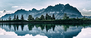 Serene Alpine Mountain Range Reflected in a Calm Lake with Pine Trees HD wallpaper