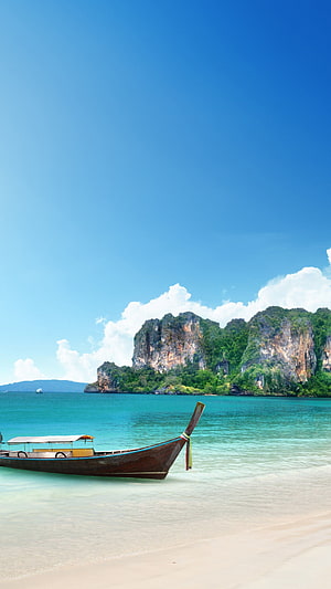 Traditional Thai Longtail Boat on a Turquoise Beach with Limestone Cliffs in the Background HD phone wallpaper