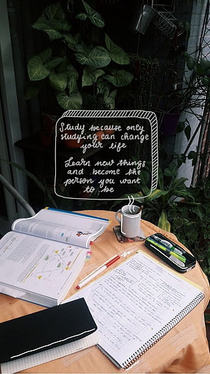 Cozy Study Desk Setup with Open Books, Handwritten Notes, and Motivational Quote Overlay HD phone wallpaper