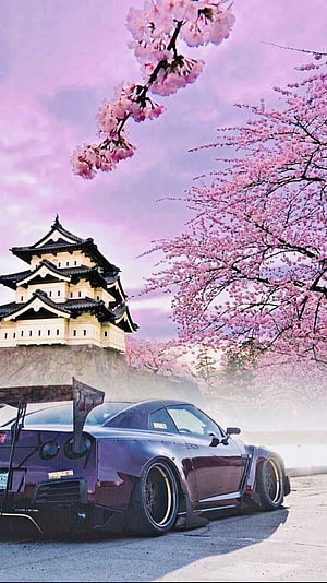 Nissan R35 GT-R with widebody kit parked beneath cherry blossoms near a Japanese castle HD phone wallpaper