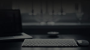 Minimalist Dark Workspace with Laptop, Keyboard, and Mouse on a Desk HD wallpaper
