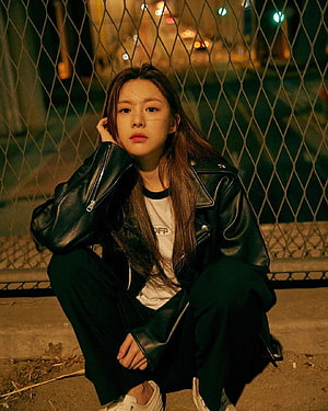 Go Yoon Jung in a black leather jacket crouching against a chain-link fence at night HD phone wallpaper