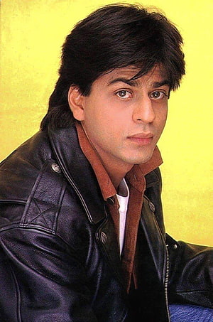 Shah Rukh Khan in a black leather jacket against a yellow background HD phone wallpaper