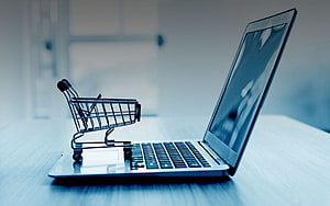 Miniature Shopping Cart on Laptop Keyboard for Online Retail Concept HD wallpaper