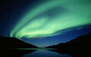 Green Aurora Borealis Dancing Over a Serene Mountain Lake at Night HD wallpaper