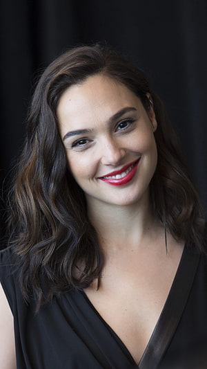 Gal Gadot smiling portrait with wavy brown hair and red lipstick against a dark background HD phone wallpaper