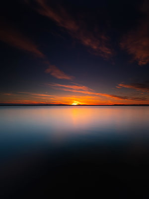Serene Lake Sunset with Vibrant Orange Sky and Calm Water Reflection HD phone wallpaper