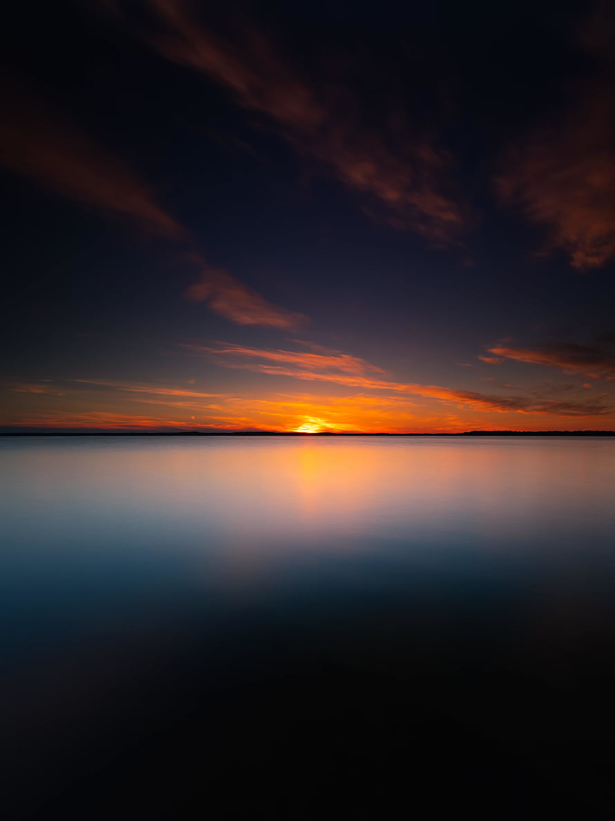 Serene Lake Sunset with Vibrant Orange Sky and Calm Water Reflection HD phone wallpaper