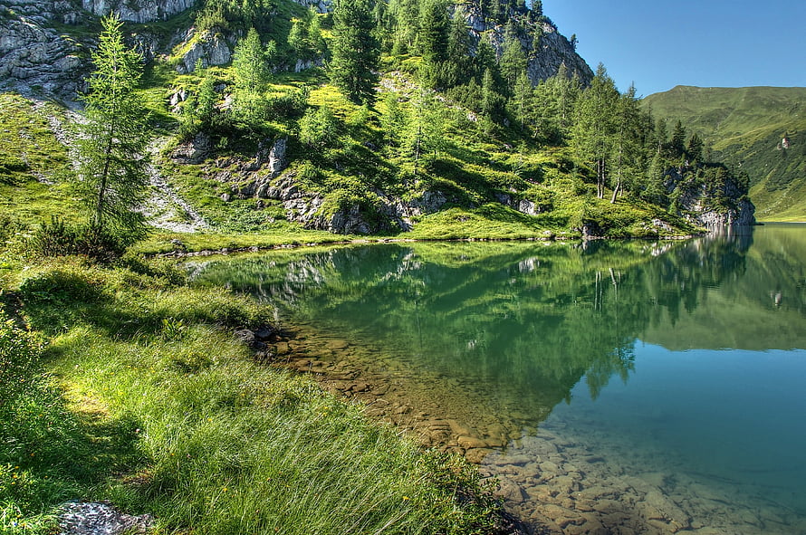 Serene Alpine Lake with Crystal Clear Waters and Lush Green Forested Hills HD wallpaper