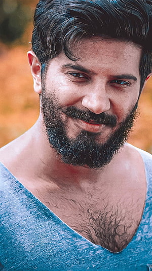 Dulquer Salman Close-Up Portrait in Blue V-Neck Shirt with Warm Autumn Background HD phone wallpaper