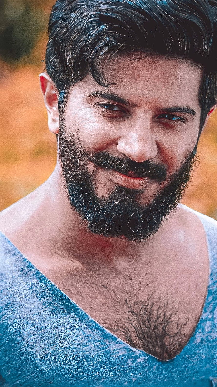 Dulquer Salman Close-Up Portrait in Blue V-Neck Shirt with Warm Autumn Background HD phone wallpaper