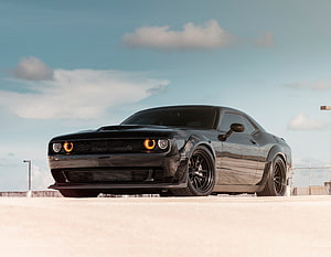 Black Dodge Challenger SRT parked on a rooftop under a blue sky with scattered clouds HD wallpaper