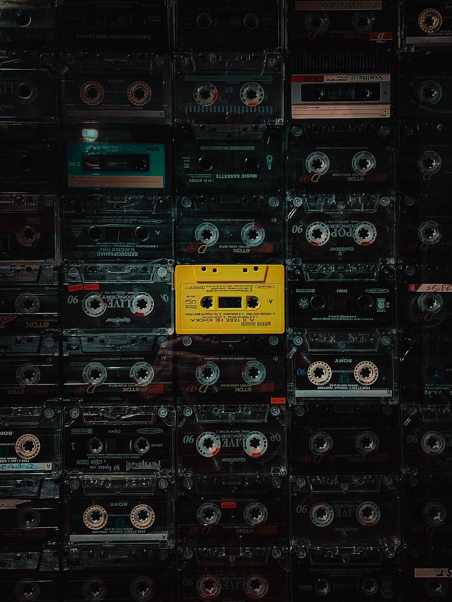 Grid of Vintage Audio Cassette Tapes with One Bright Yellow Shell HD phone wallpaper