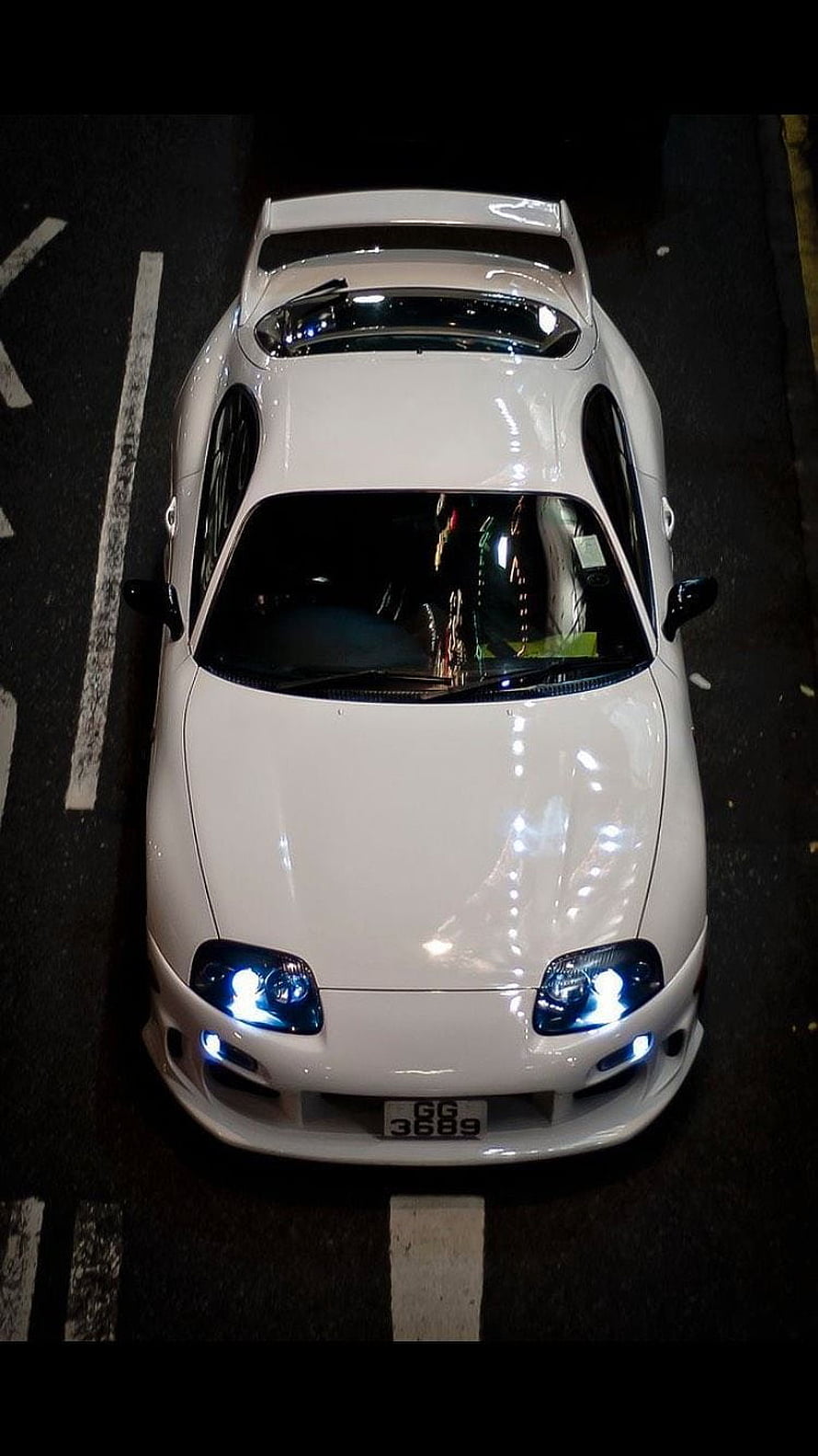 Top-Down View of a White Toyota Supra Parked on a Street at Night with Blue Headlights HD phone wallpaper