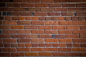 Close-up of a weathered red brick wall with textured mortar lines and warm earthy tones HD wallpaper