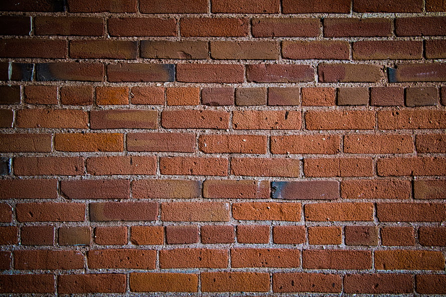 Close-up of a weathered red brick wall with textured mortar lines and warm earthy tones HD wallpaper