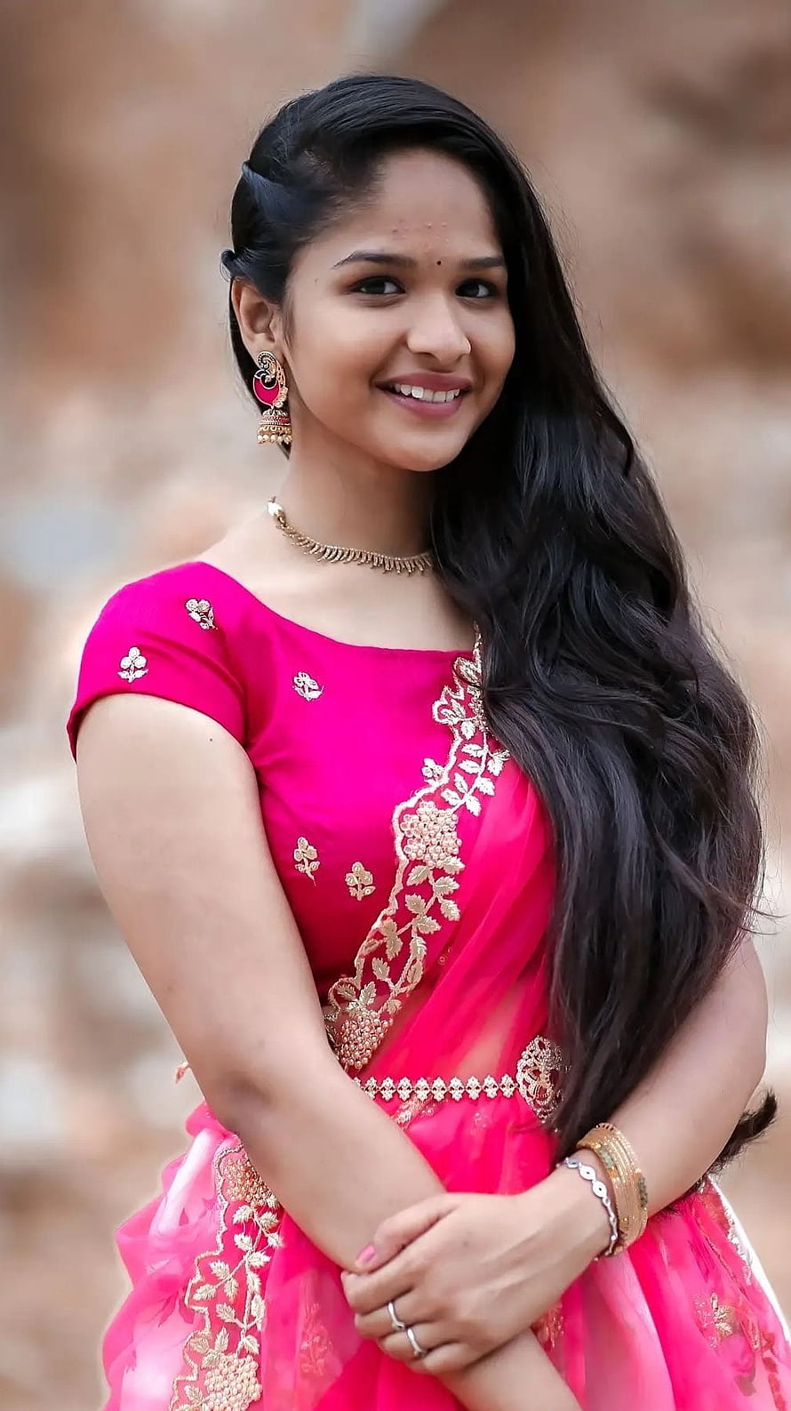 Nithya in a vibrant pink embroidered lehenga with gold jewelry and long dark hair HD phone wallpaper