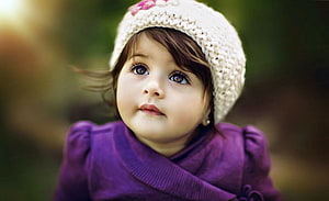Adorable Toddler Girl Wearing a Knit Beanie and Purple Jacket in a Soft Outdoor Portrait HD wallpaper
