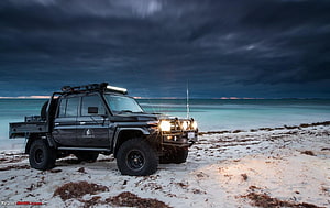 Black Toyota Land Cruiser 70 Series Pickup on a Stormy Beach at Dusk HD wallpaper