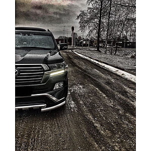 Black Toyota Land Cruiser ZX on a wet gravel road under a moody overcast sky HD phone wallpaper
