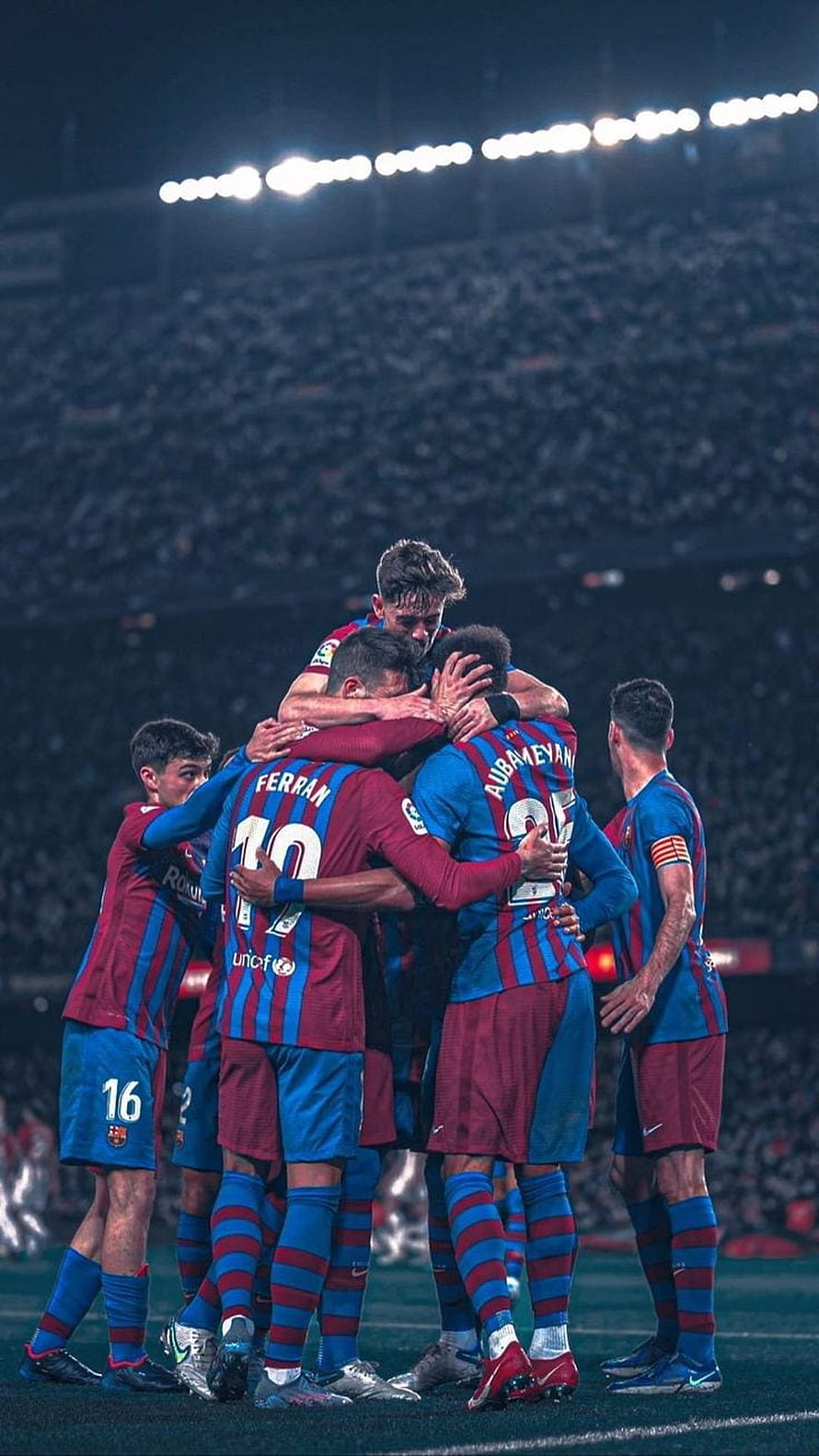 FC Barcelona players in a celebratory huddle on the pitch under stadium lights HD phone wallpaper