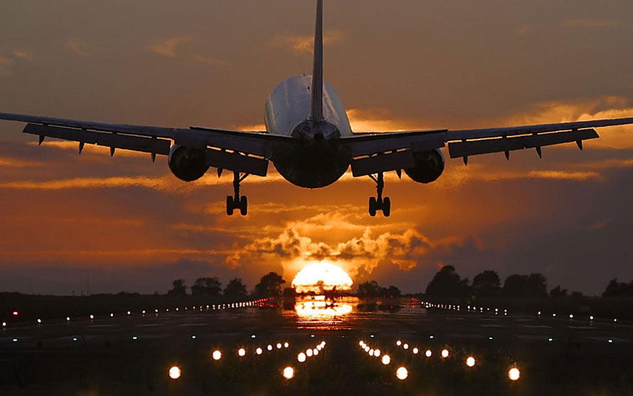 Commercial Jetliner Silhouetted Against Dramatic Sunset During Final Approach HD wallpaper