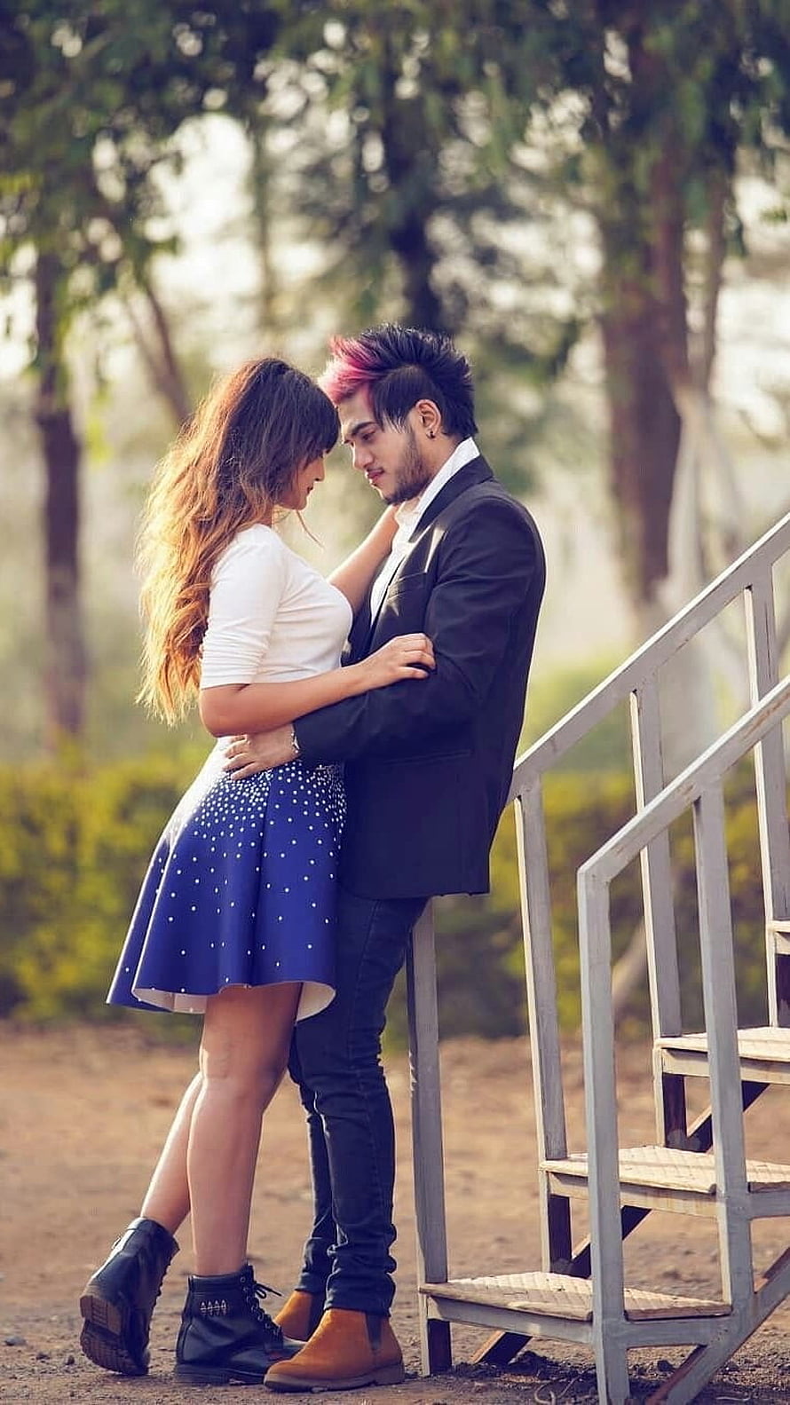 Romantic couple embracing outdoors in a park with soft natural lighting HD phone wallpaper