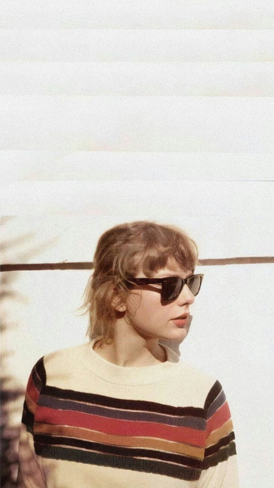 Taylor Swift in striped sweater and sunglasses against a bright white wall HD phone wallpaper