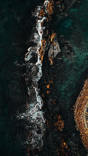 Aerial View of Turquoise Ocean Waves Crashing Against Dark Rocky Coastline HD phone wallpaper