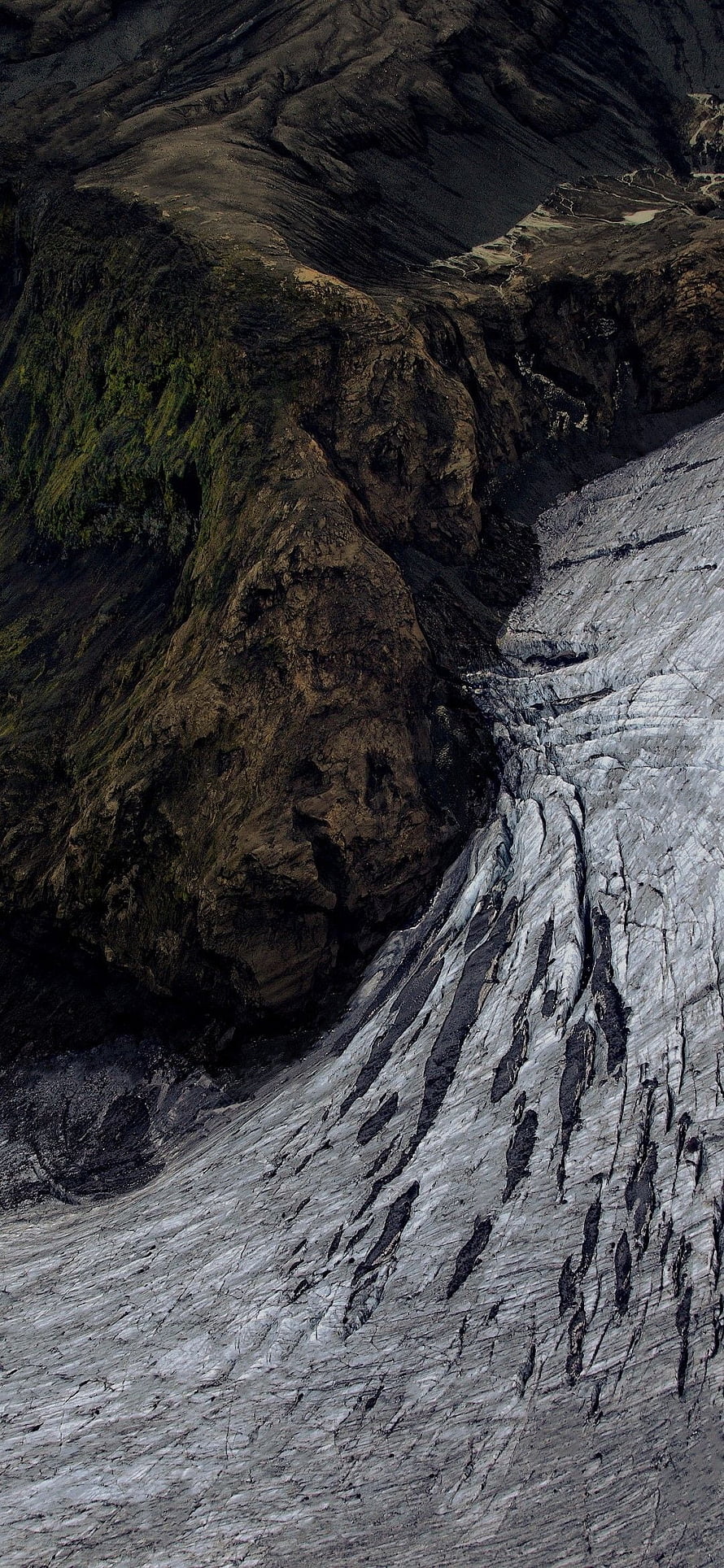 Aerial View of Rugged Mountain Terrain with Glacial Ice and Dark Rock Formations HD phone wallpaper
