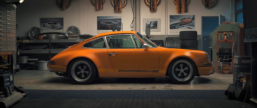 Classic Orange Porsche 911 Coupe Parked in a Well-Equipped Automotive Workshop HD wallpaper