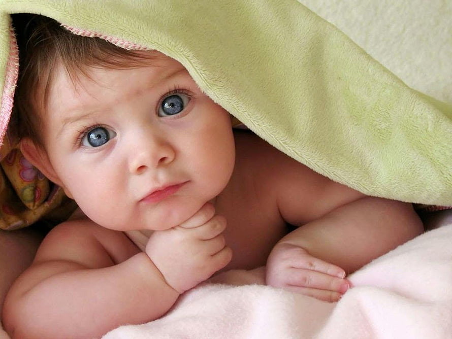 Adorable Baby Boy With Blue Eyes Resting Chin On Hand Under Soft Green Blanket HD wallpaper