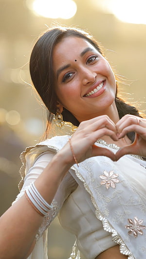 Srinidhi Shetty in White Ethnic Wear Making a Heart Gesture with Golden Backlight HD phone wallpaper