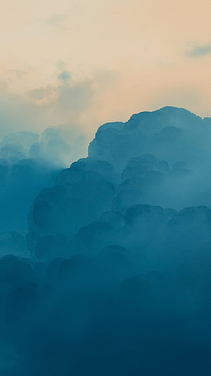 Serene Blue Cumulus Clouds Against a Soft Peach Sky at Dusk HD phone wallpaper