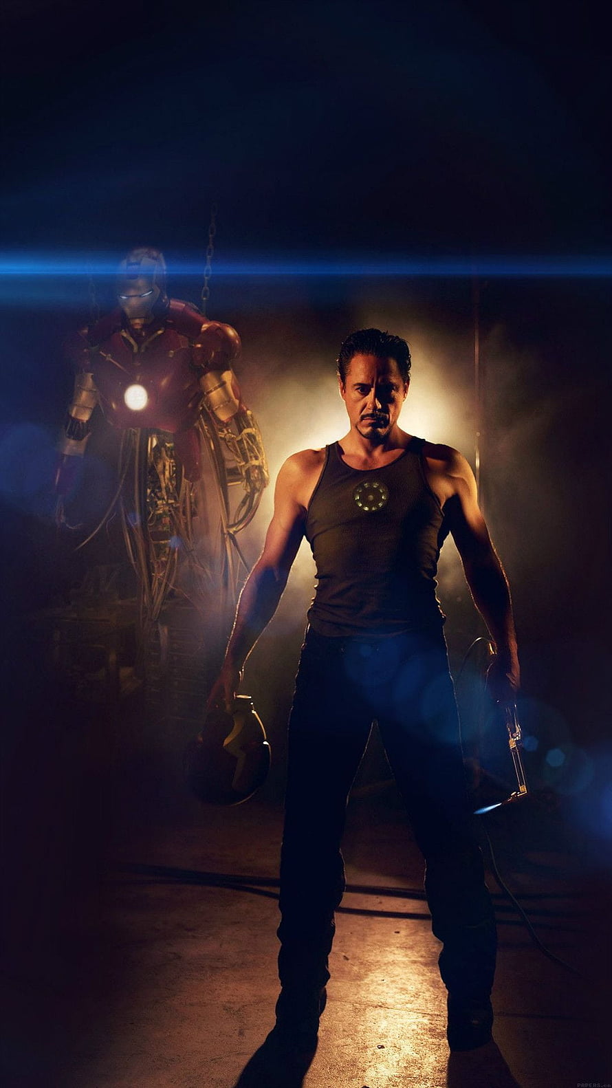 Tony Stark and Iron Man Armor in a Dramatic Workshop Scene HD phone wallpaper