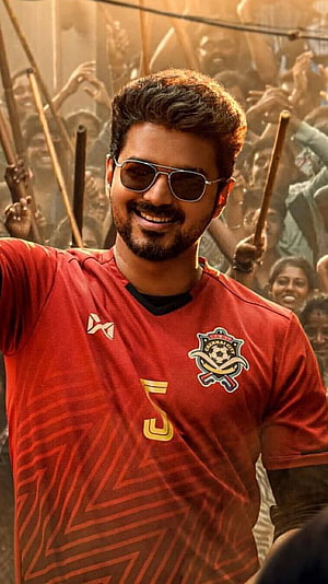 Vijay in red Chennai FC jersey with sunglasses and beaming smile amid cheering crowd HD phone wallpaper