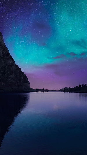 Vibrant Aurora Borealis Over a Serene Mountain Lake at Night HD phone wallpaper