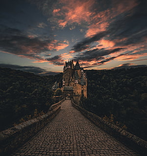 Medieval Castle on a Cobblestone Bridge at Sunset with Dramatic Clouds HD phone wallpaper