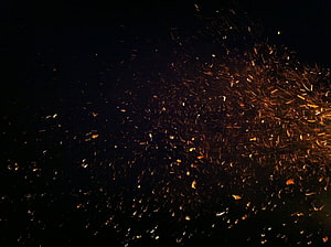 Glowing Fire Sparks and Embers Scattering Against a Deep Black Night Sky HD wallpaper