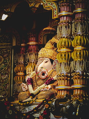 Ornate Ganesha Temple Idol Adorned With Gold Crown, Pearls, and Floral Garlands HD phone wallpaper