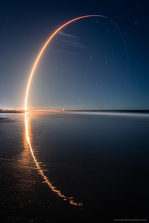 SpaceX Starlink Rocket Launch Light Trail Arcing Over a Dark Shoreline at Night HD phone wallpaper
