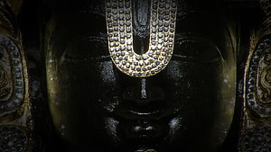 Close-up of Lord Venkateswara statue with ornate forehead ornament and dark polished surface HD wallpaper