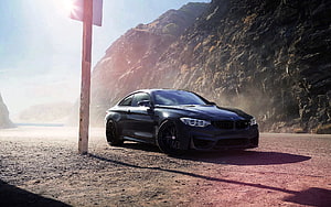Black BMW M4 F82 Coupe Parked on a Dusty Mountain Road with Rocky Cliffs and Sun Flare HD wallpaper