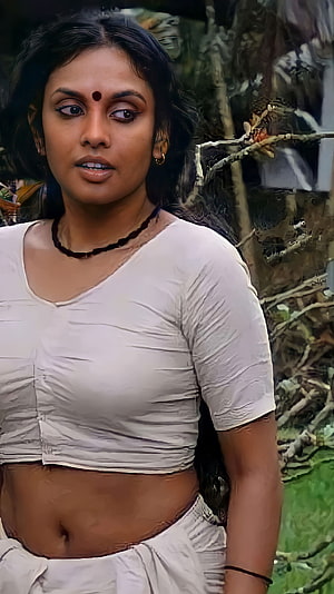 Jothirmayi in a white crop top with a bindi and beaded necklace in a natural outdoor setting HD phone wallpaper